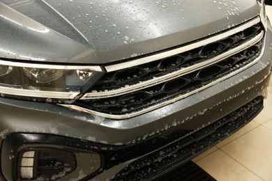 Auto covered with cleaning foam at car wash, closeup