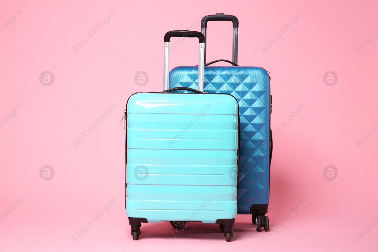 Photo of Two new color suitcases on pink background