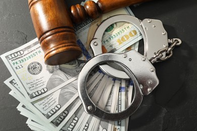 Handcuffs with dollar banknotes and wooden gavel on grey textured table, flat lay