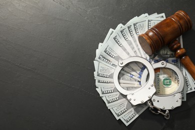 Photo of Handcuffs with dollar banknotes and wooden gavel on grey textured table, flat lay. Space for text