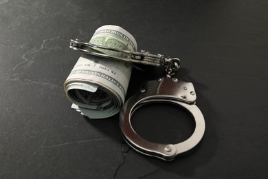 Handcuffs with dollar banknotes on grey textured table