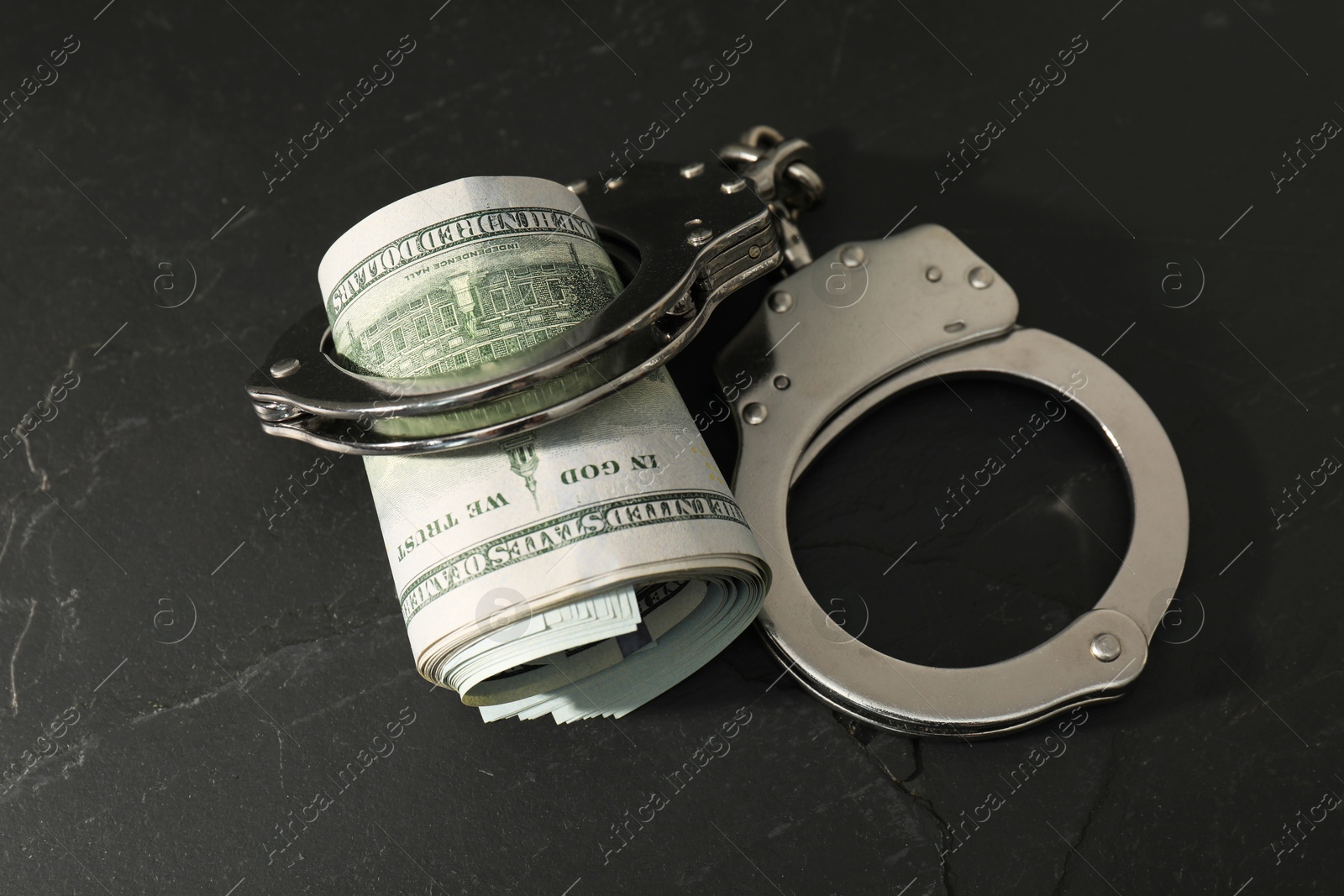 Photo of Handcuffs with dollar banknotes on grey textured table