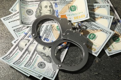 Photo of Handcuffs with dollar banknotes on grey textured table