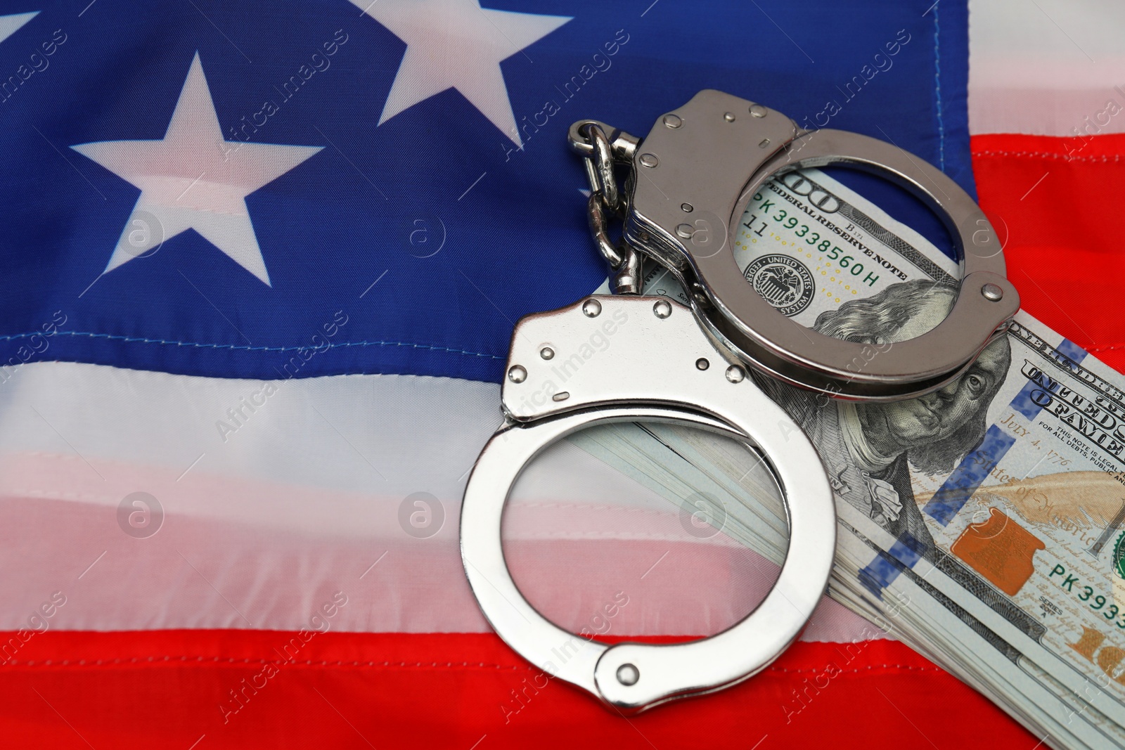 Photo of Handcuffs with dollar banknotes on American flag, space for text