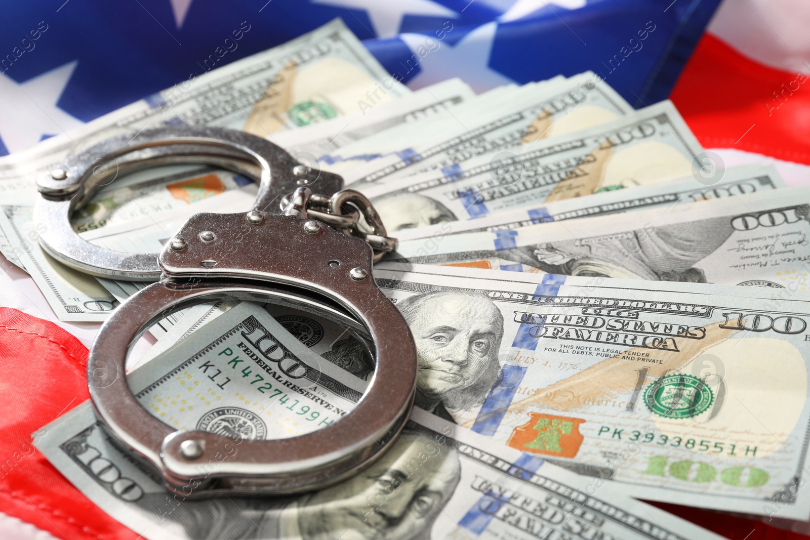 Photo of Handcuffs with dollar banknotes on American flag, closeup