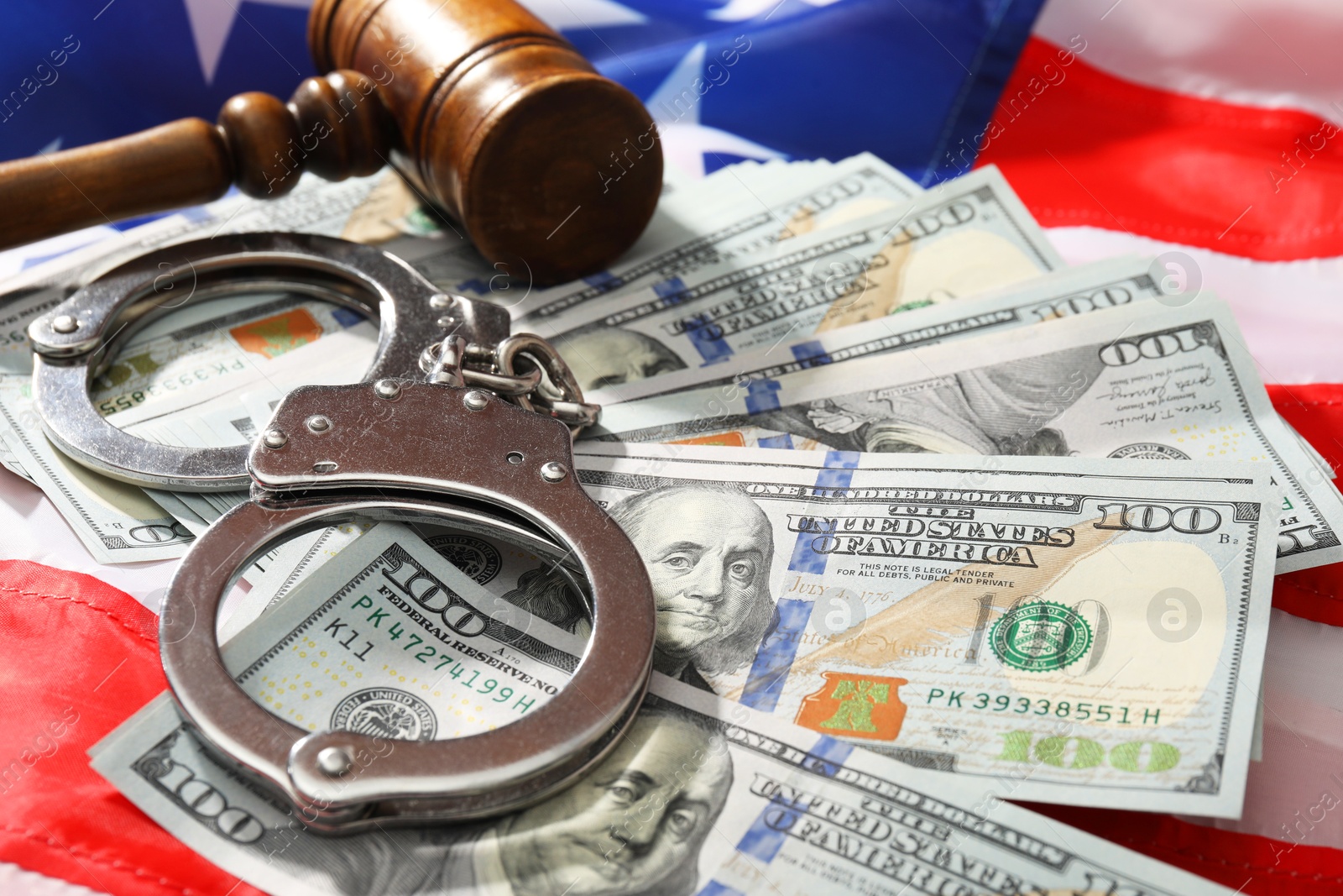 Photo of Handcuffs with dollar banknotes and wooden gavel on American flag