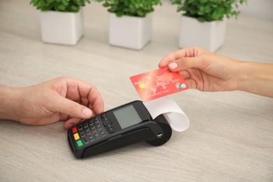 Photo of Man taking payment from client via credit card terminal at wooden table, closeup