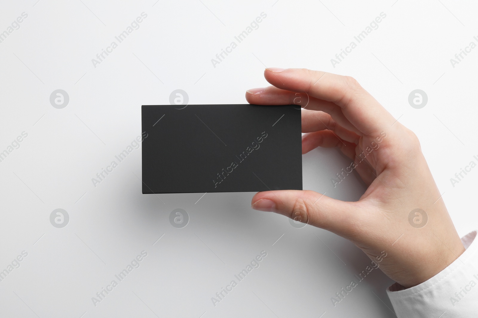 Photo of Woman with blank business card on light grey background, closeup. Mockup for design