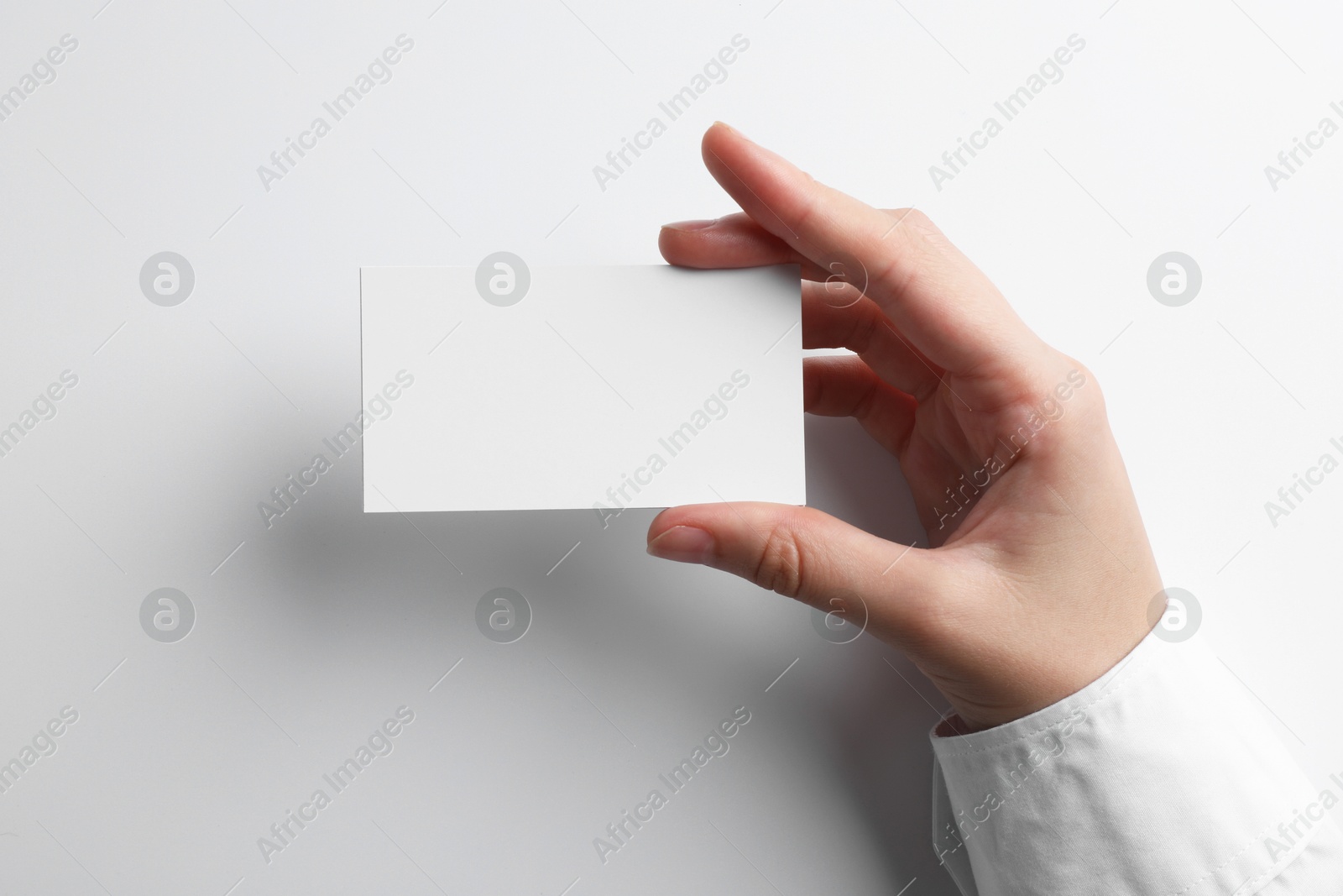 Photo of Woman with blank business card on light grey background, closeup. Mockup for design