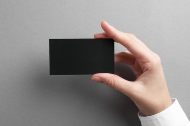 Photo of Woman with blank business card on grey background, closeup. Mockup for design