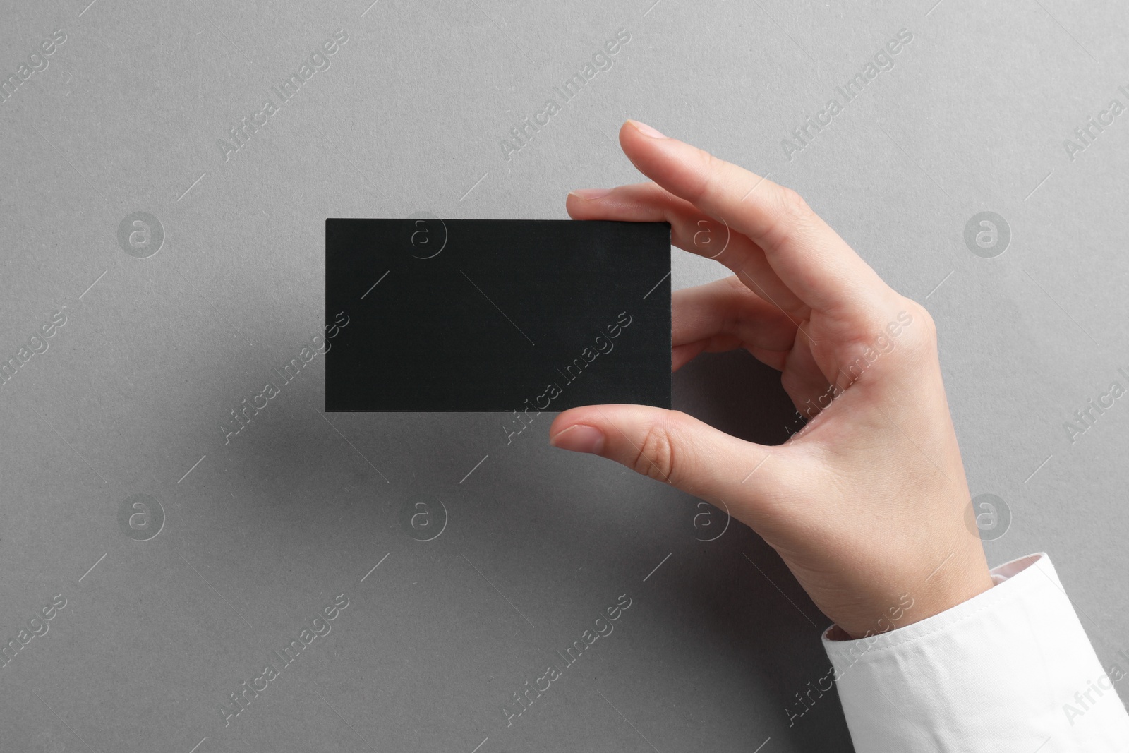 Photo of Woman with blank business card on grey background, closeup. Mockup for design