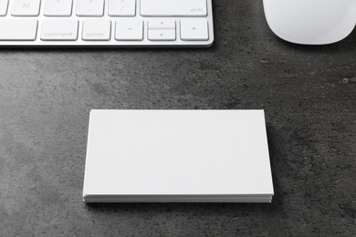 Blank business cards, computer mouse and keyboard on grey textured table. Mockup for design