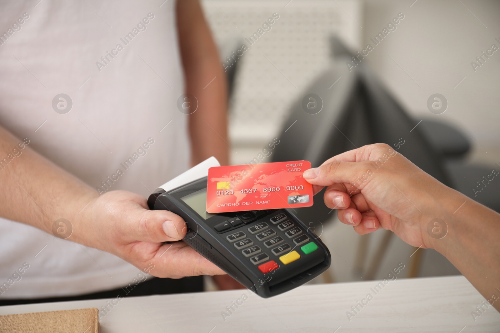 Photo of Man taking payment from client via credit card terminal indoors, closeup