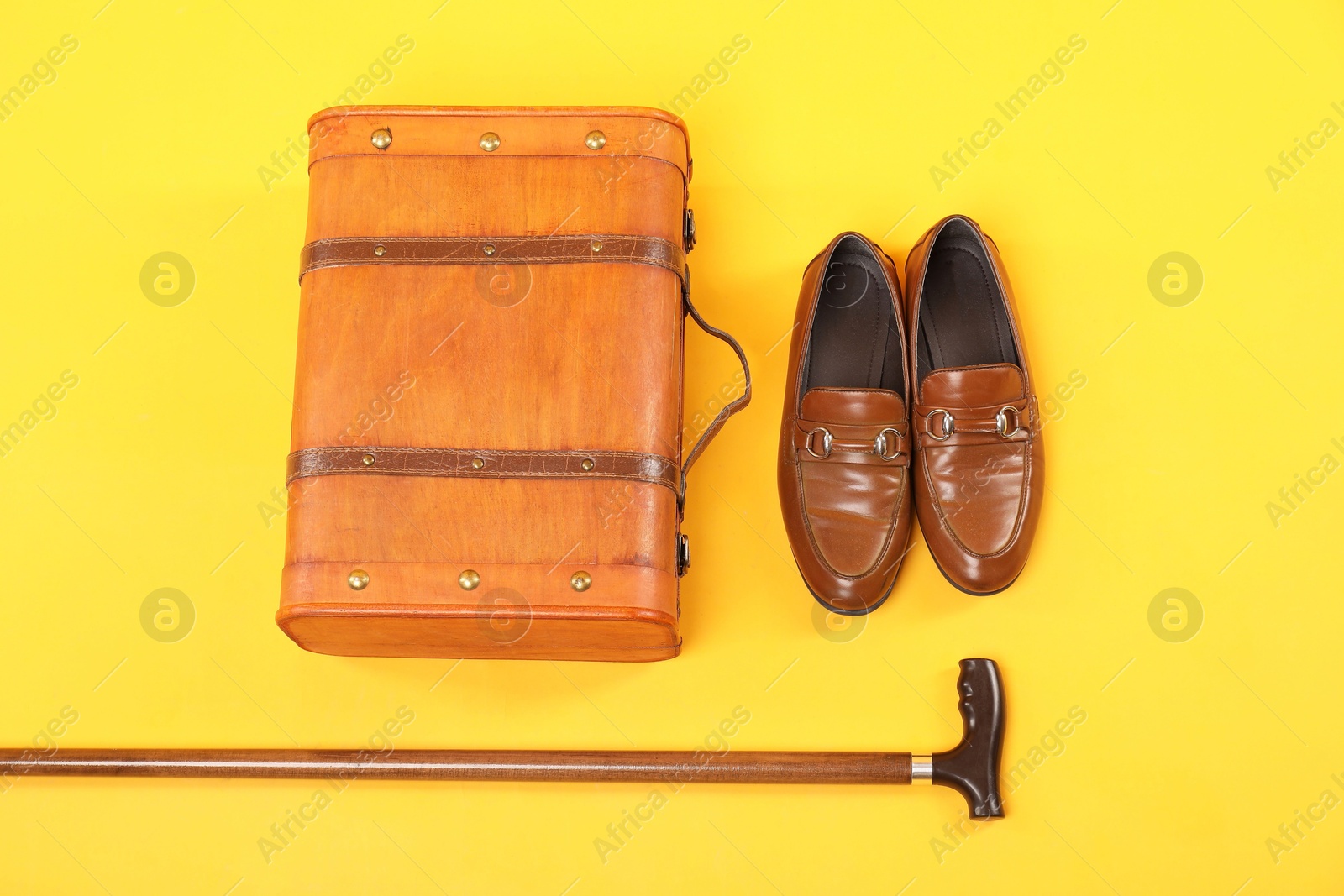 Photo of Suitcase, shoes and cane on yellow background, flat lay