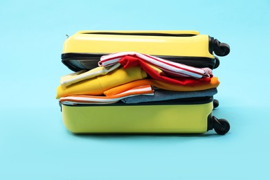 Photo of One suitcase with clothes on light blue background