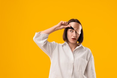 Photo of Overslept young woman with sleep mask on yellow background