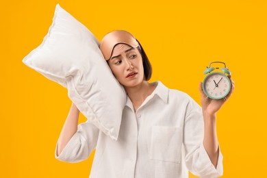 Photo of Overslept young woman with sleep mask, pillow and alarm clock on yellow background