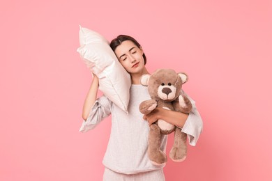 Photo of Overslept young woman with teddy bear and pillow on pink background