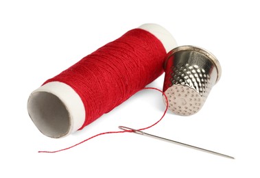 Photo of Thimble and needle with red sewing thread isolated on white