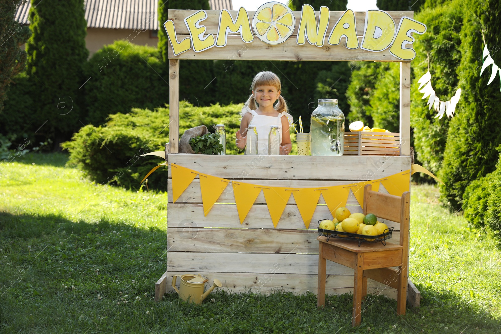 Photo of Cute little girl with refreshing drink at lemonade stand in park