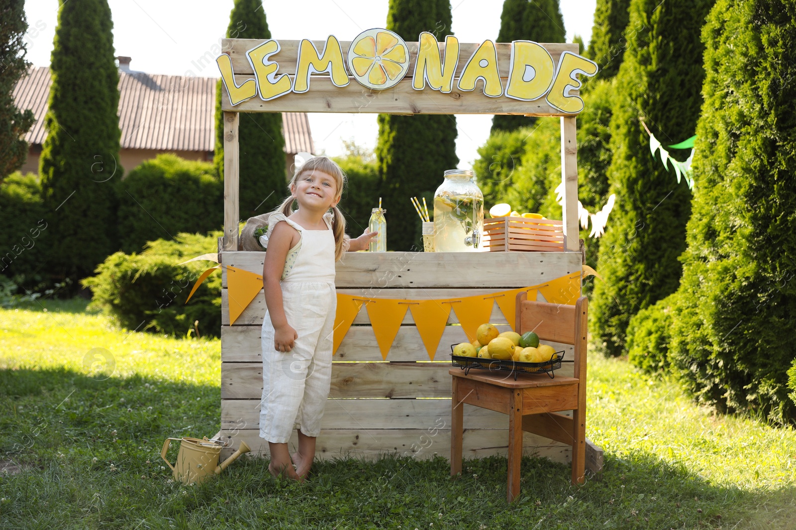 Photo of Little girl with refreshing drink near lemonade stand in park