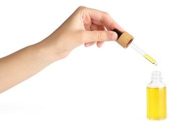 Photo of Woman dripping tincture from pipette into bottle on white background, closeup