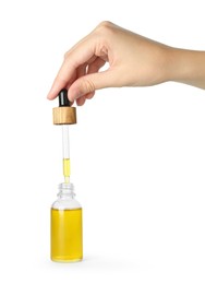 Photo of Woman dripping tincture from pipette into bottle on white background, closeup