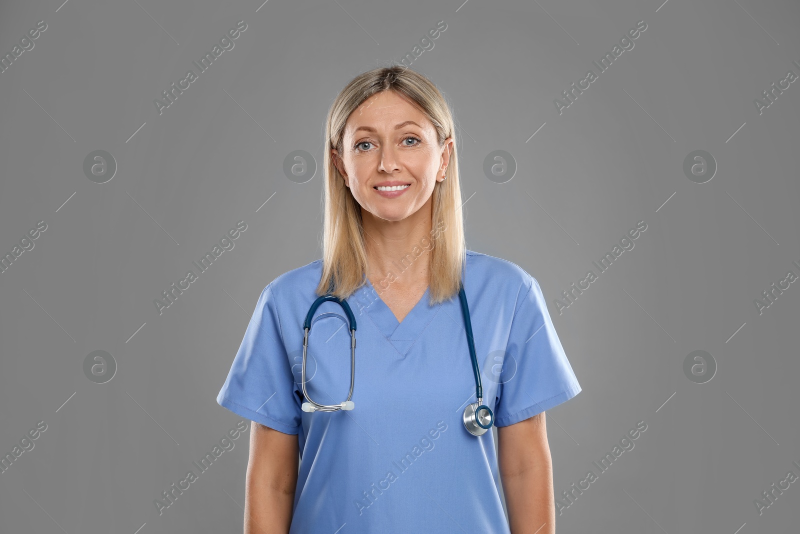 Photo of Portrait of doctor in medical uniform with stethoscope on grey background