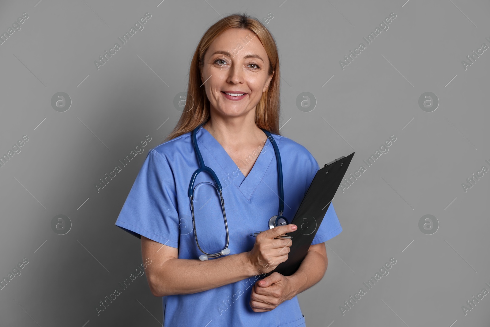 Photo of Doctor with stethoscope and clipboard on gray background