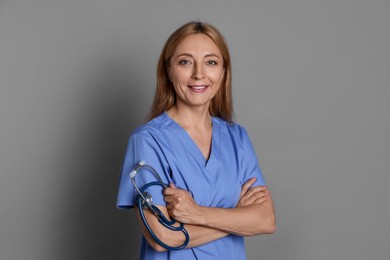 Smiling doctor with stethoscope on gray background