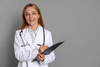 Doctor with clipboard writing notes on gray background, space for text