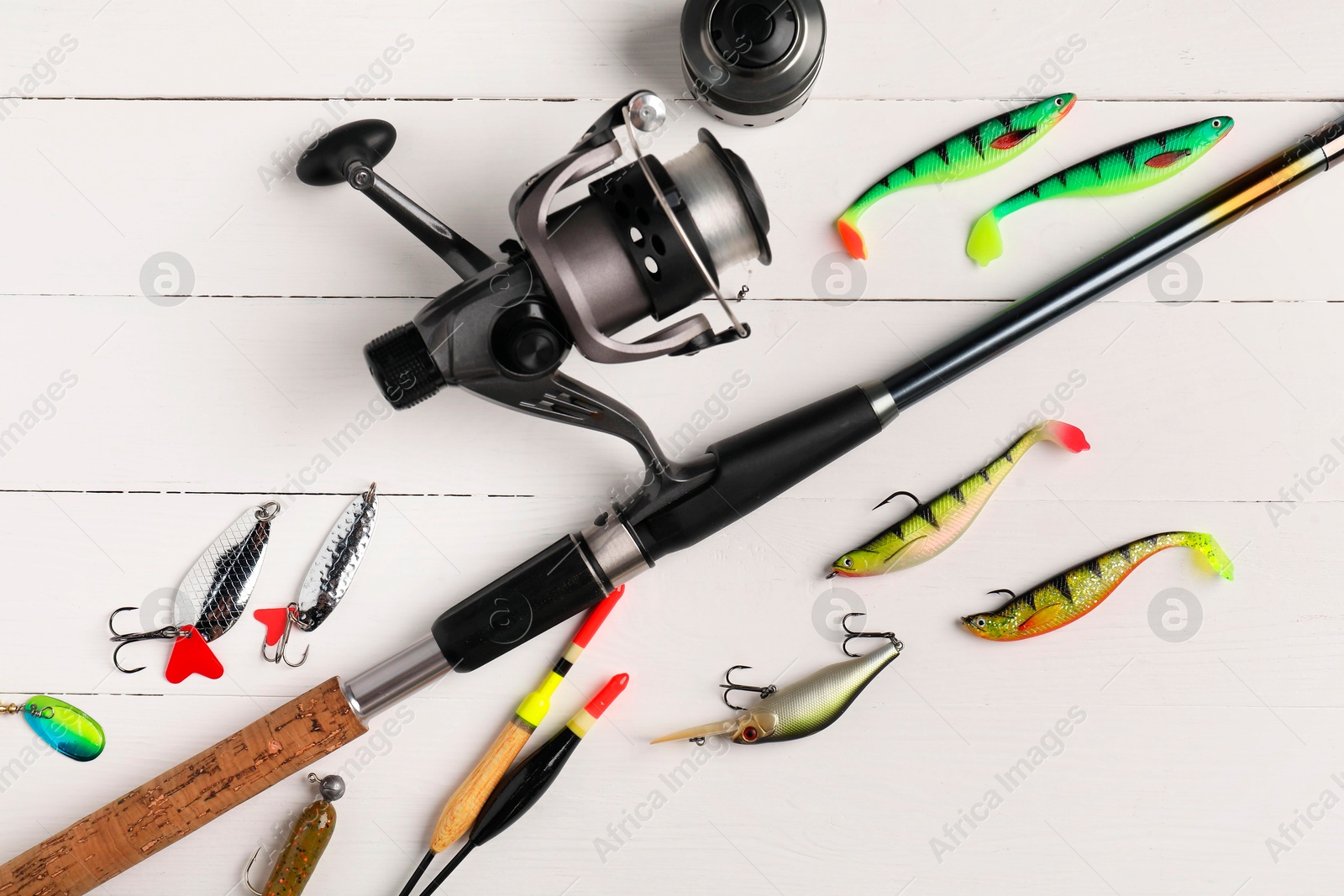 Photo of Fishing rod with spinning reel, baits and floats on white wooden table, flat lay