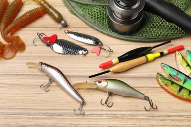 Fishing baits, floats, net and spinning reel on wooden table