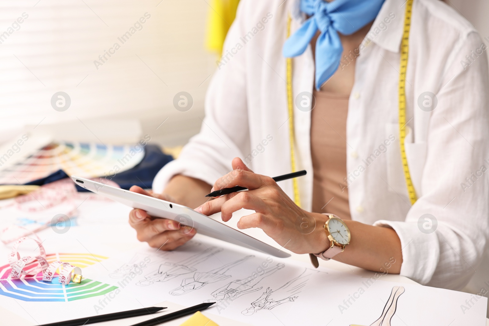 Photo of Fashion designer with tablet working at table in workshop, closeup