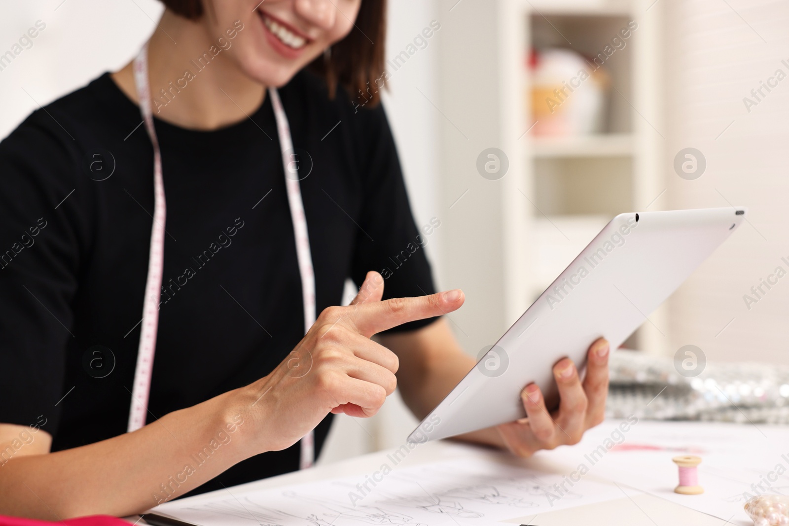 Photo of Fashion designer with tablet working in workshop, closeup