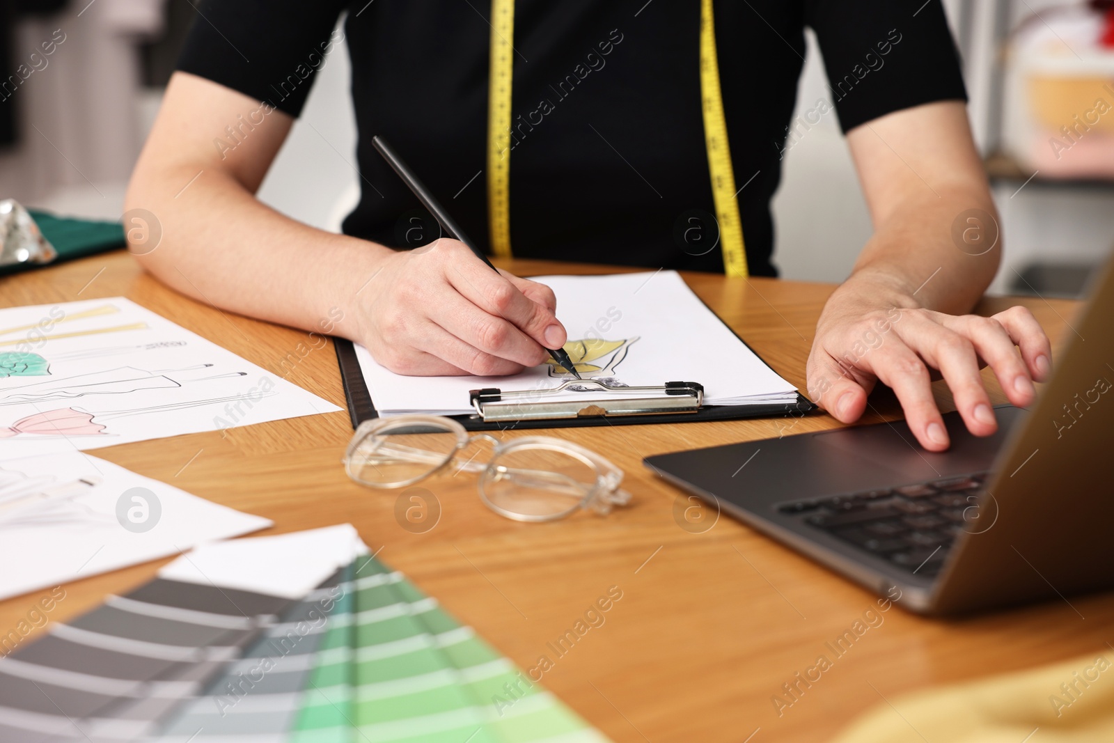 Photo of Fashion designer drawing sketch of beautiful dress at wooden table, closeup