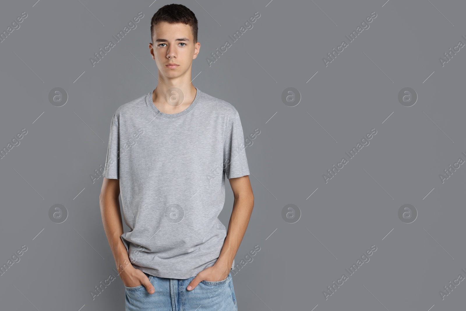 Photo of Teenage boy wearing t-shirt on grey background, space for text