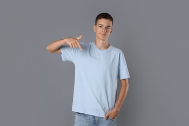 Photo of Teenage boy wearing light blue t-shirt on grey background