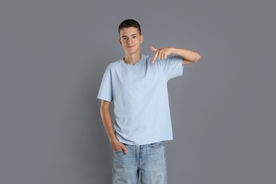 Photo of Teenage boy wearing light blue t-shirt on grey background