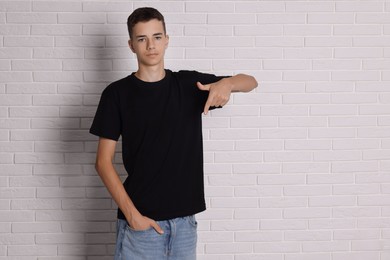 Photo of Teenage boy wearing black t-shirt near white brick wall, space for text