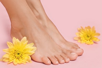 Photo of Woman with smooth feet and flowers on pink background, closeup