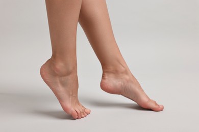 Photo of Woman with smooth feet on grey background, closeup