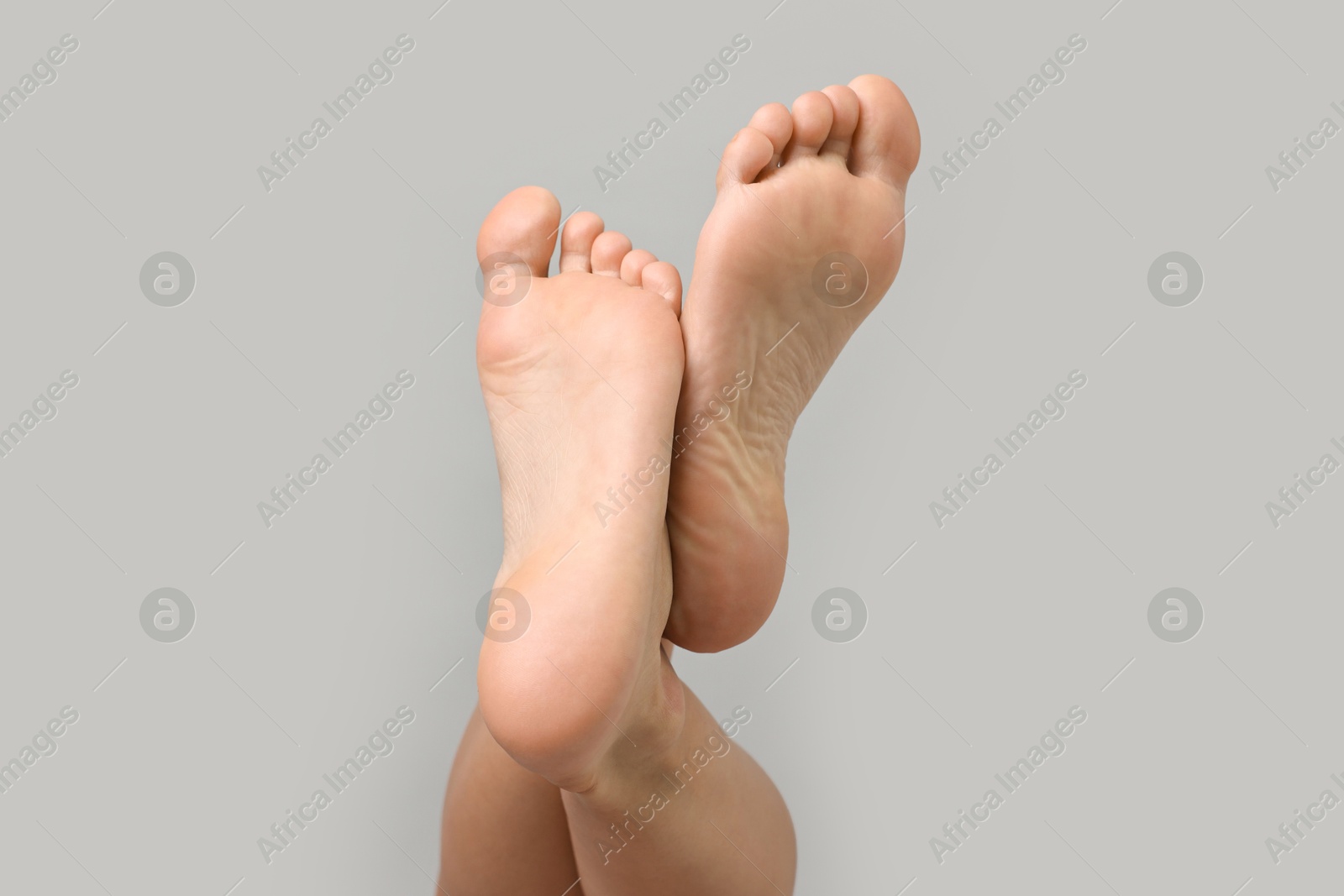 Woman with smooth feet on grey background, closeup Photo of Woman with smooth feet on grey background, closeup