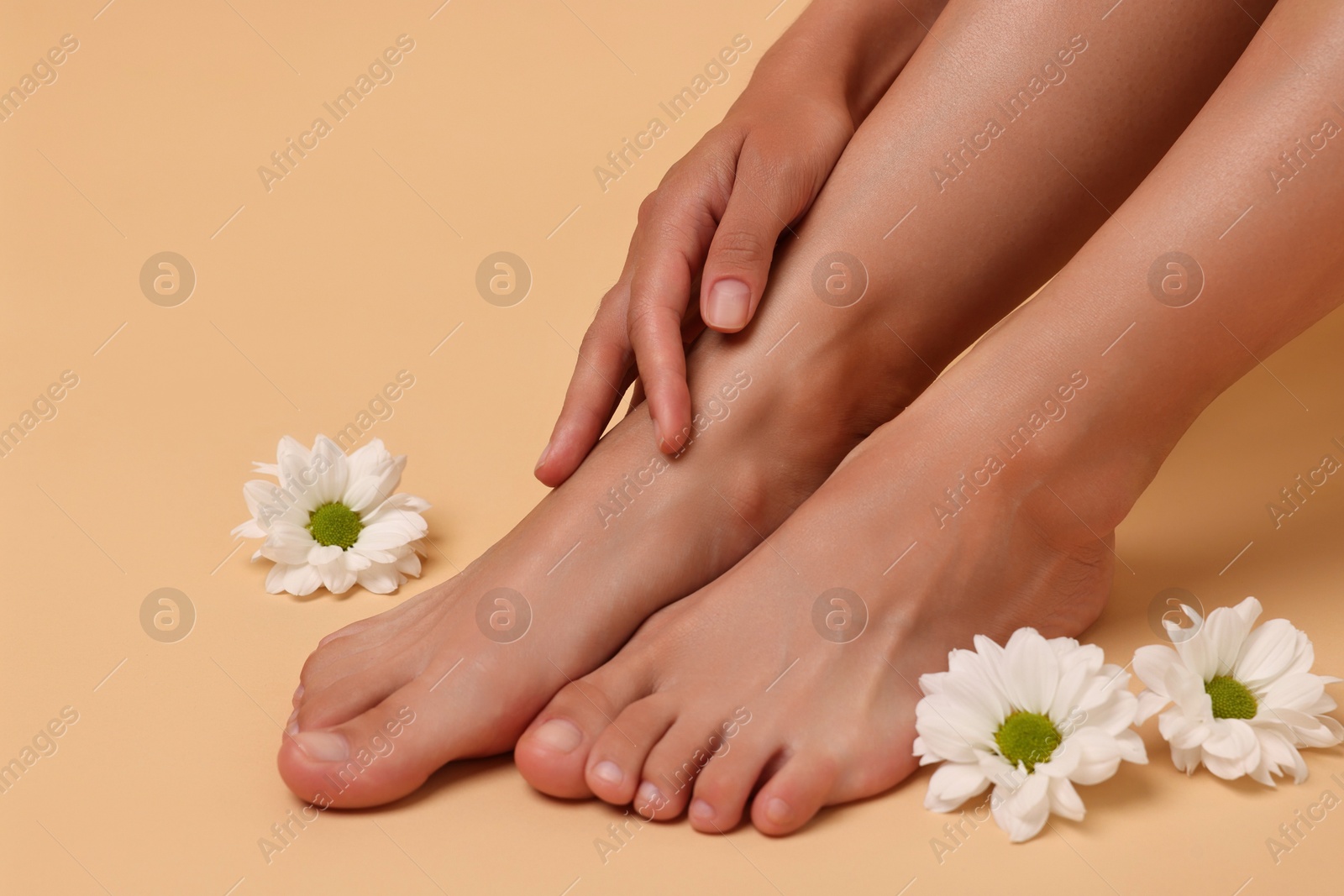 Photo of Woman touching her smooth feet on beige background, closeup