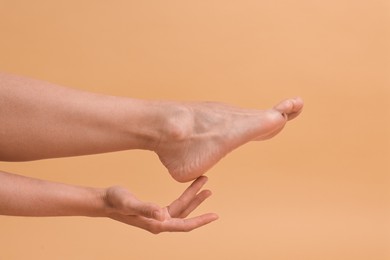 Photo of Woman touching her smooth feet on beige background, closeup