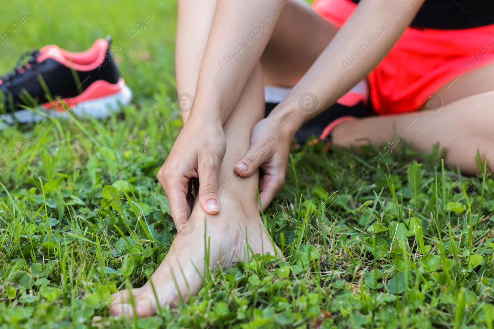 Photo of Woman suffering from foot pain on green grass outdoors, closeup