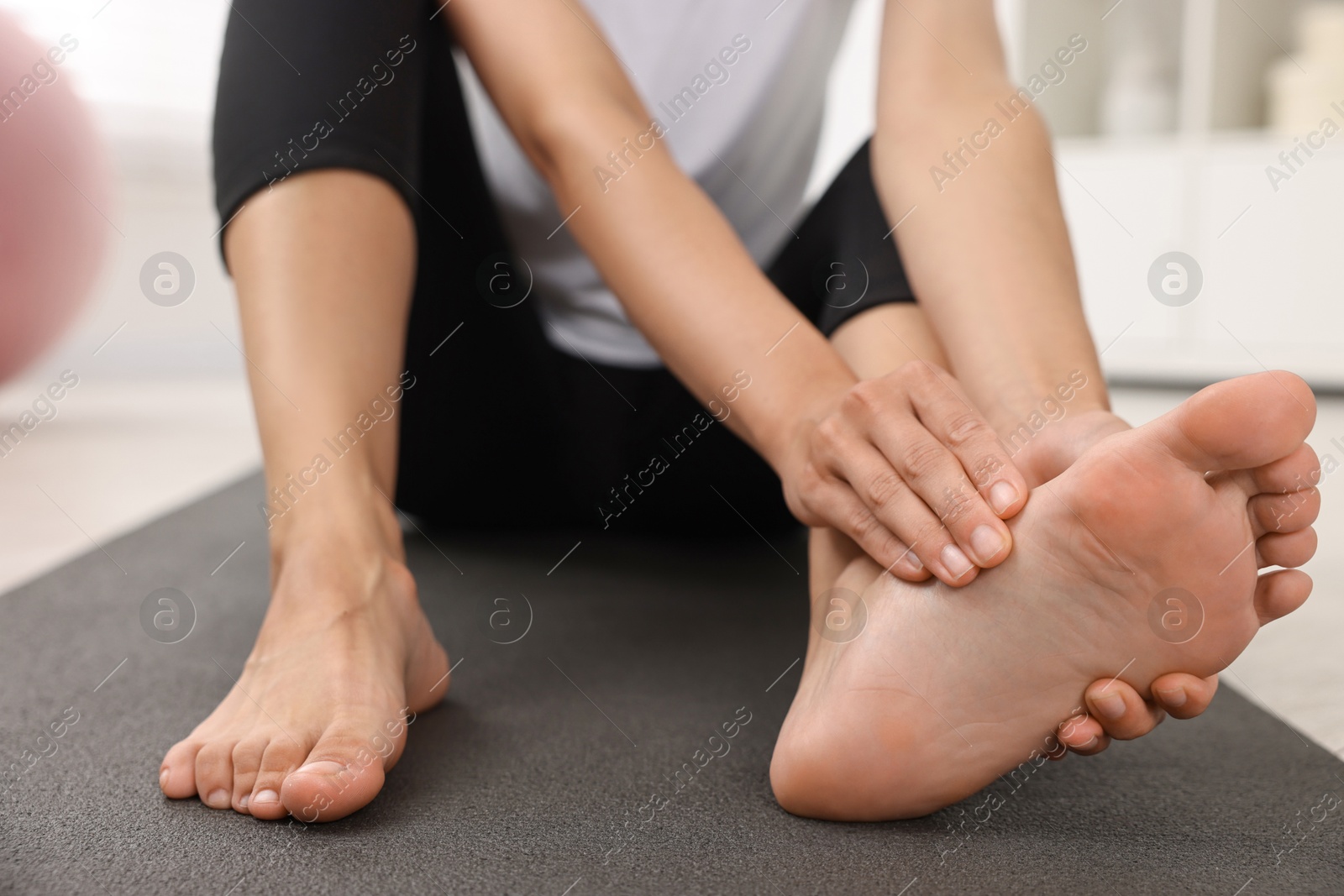 Photo of Woman suffering from foot pain at home, closeup