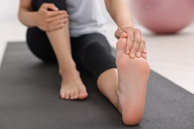 Photo of Woman suffering from foot pain at home, closeup