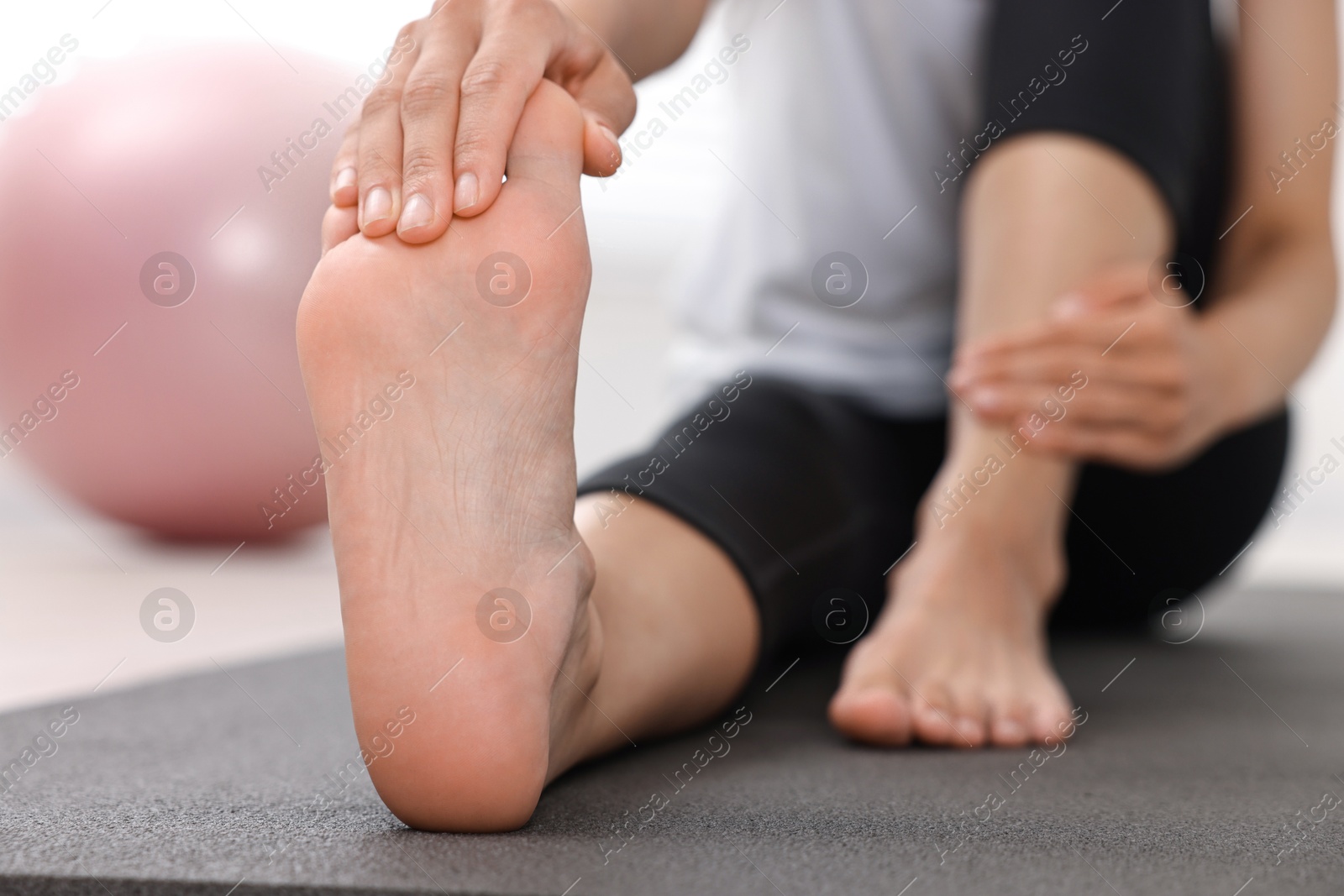 Photo of Woman suffering from foot pain at home, closeup