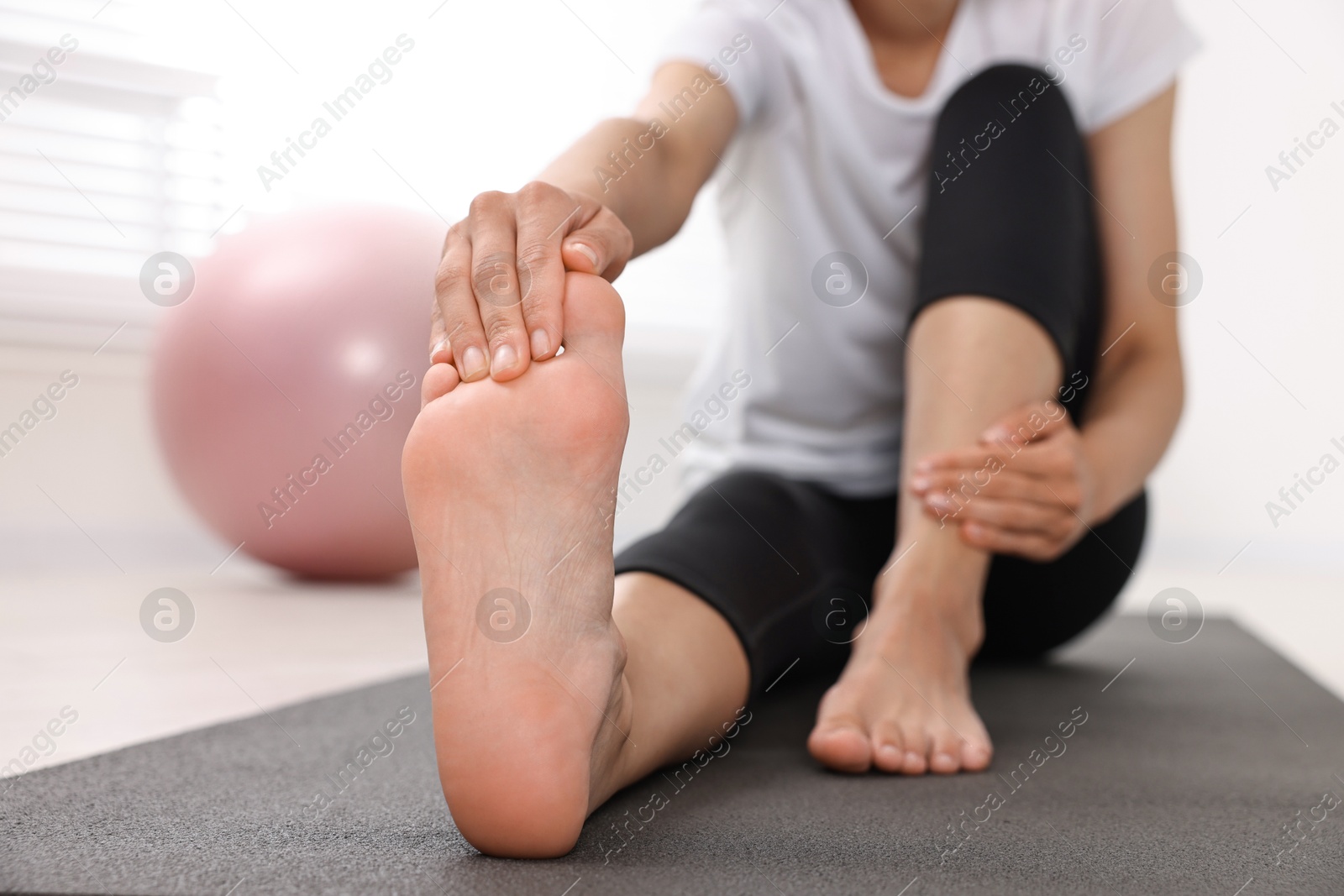 Photo of Woman suffering from foot pain at home, closeup